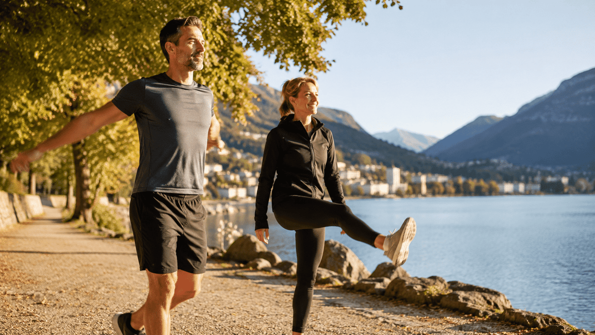 Un homme et une femme font des exercices d’assouplissement au bord d’un lac, sous le soleil du matin
